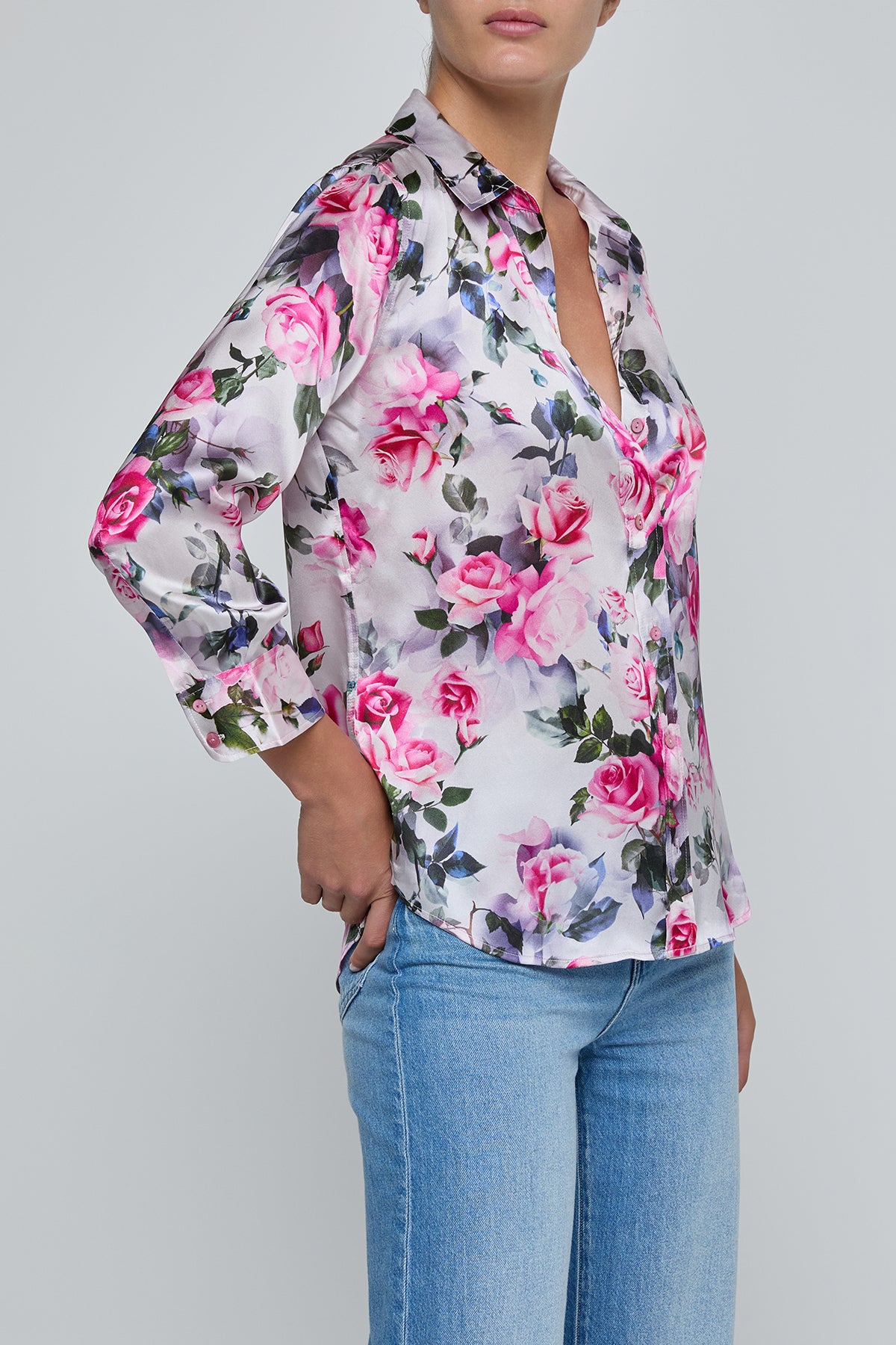 Person wearing a floral blouse and jeans on a gray background