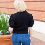 Knit sweater with puff sleeves and pom pom texture, styled with denim.