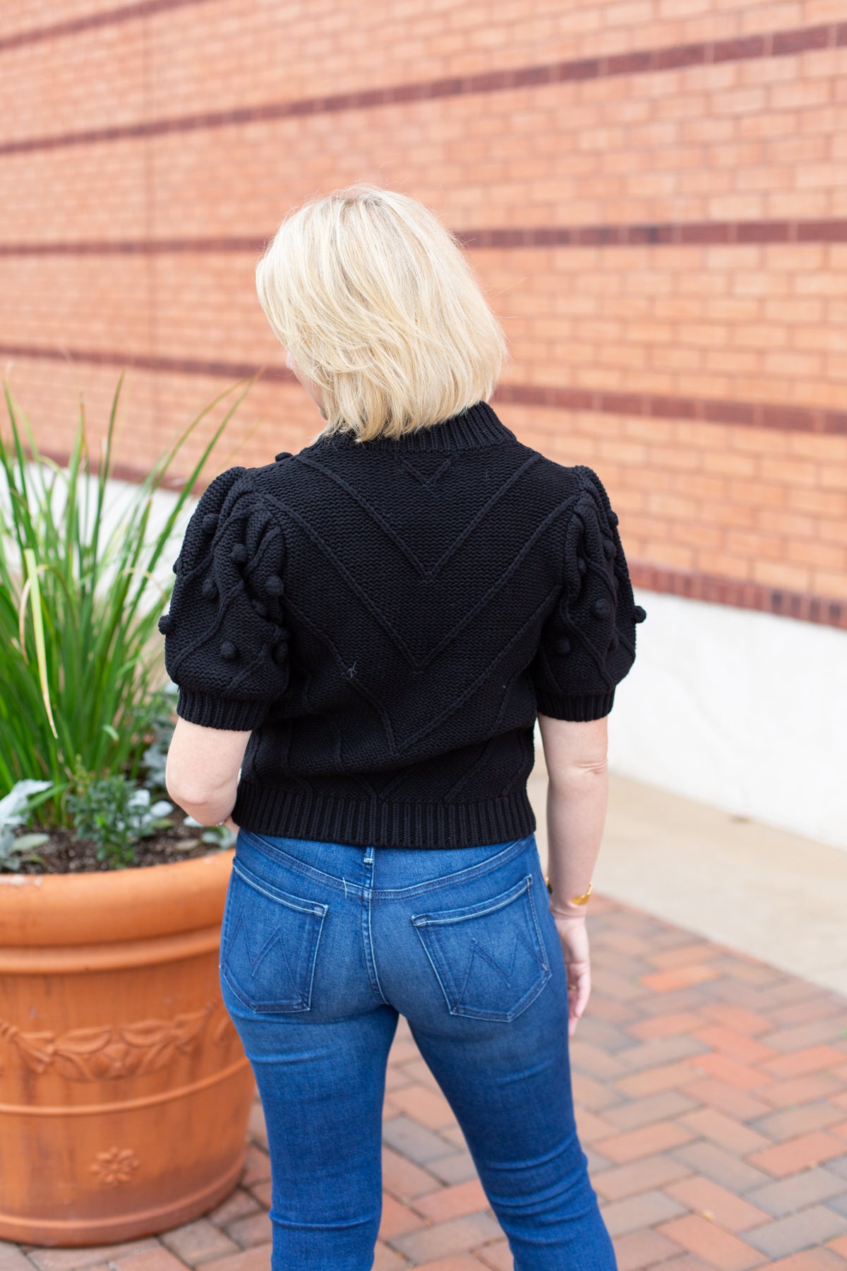 Knit sweater with puff sleeves and pom pom texture, styled with denim.
