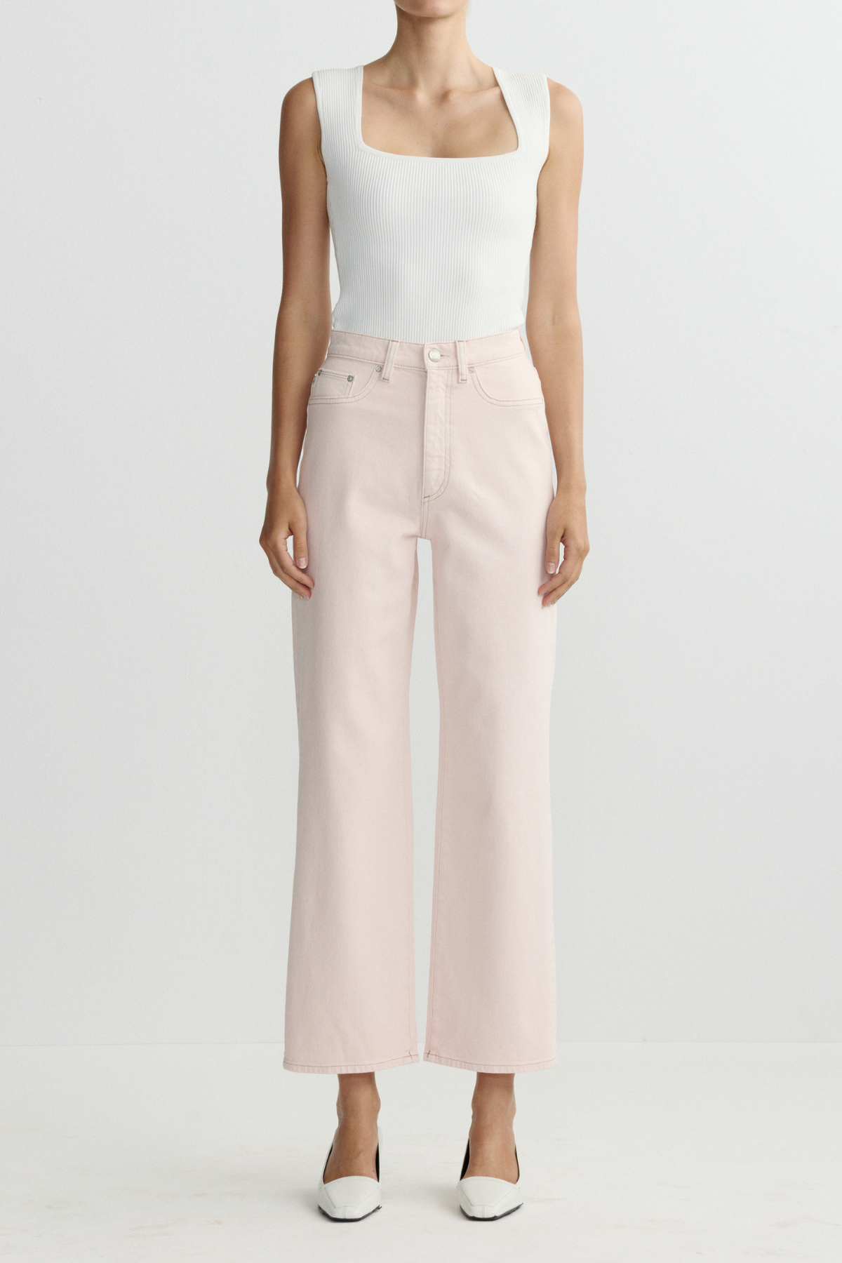 Person wearing a white sleeveless top and light pink wide-leg pants on a white background