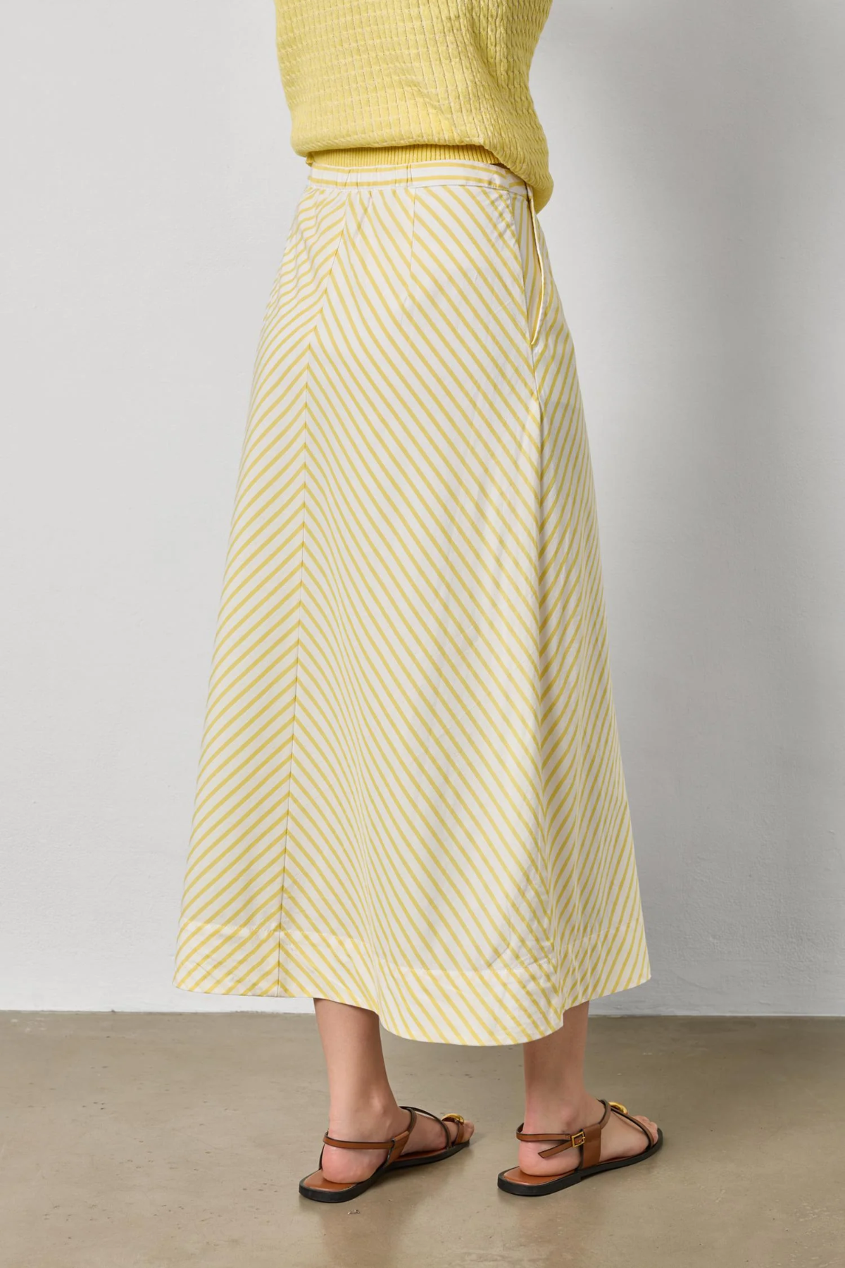 Person wearing a yellow and white striped skirt with a plain background