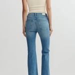 Person wearing a cream top and blue jeans on a white background