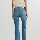 Person wearing a cream top and blue jeans on a white background