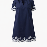 Navy blue dress with white lace details on a white background