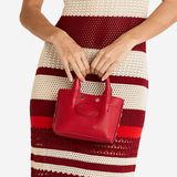 Small structured red tote bag with dual top handles and a compact, polished silhouette.