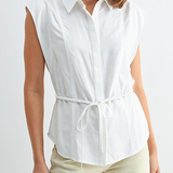 Woman wearing a white sleeveless blouse with a tie waist on a plain background