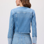 Woman wearing a denim jacket and skirt set on a white background