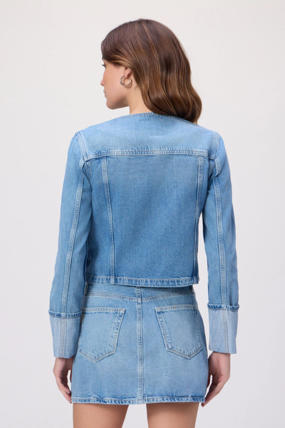 Woman wearing a denim jacket and skirt set on a white background