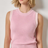 Woman wearing a pink sleeveless knitted top against a plain background