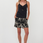 Woman wearing a black tank top and leaf-patterned shorts on a white background