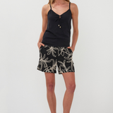 Woman wearing a black tank top and leaf-patterned shorts on a white background