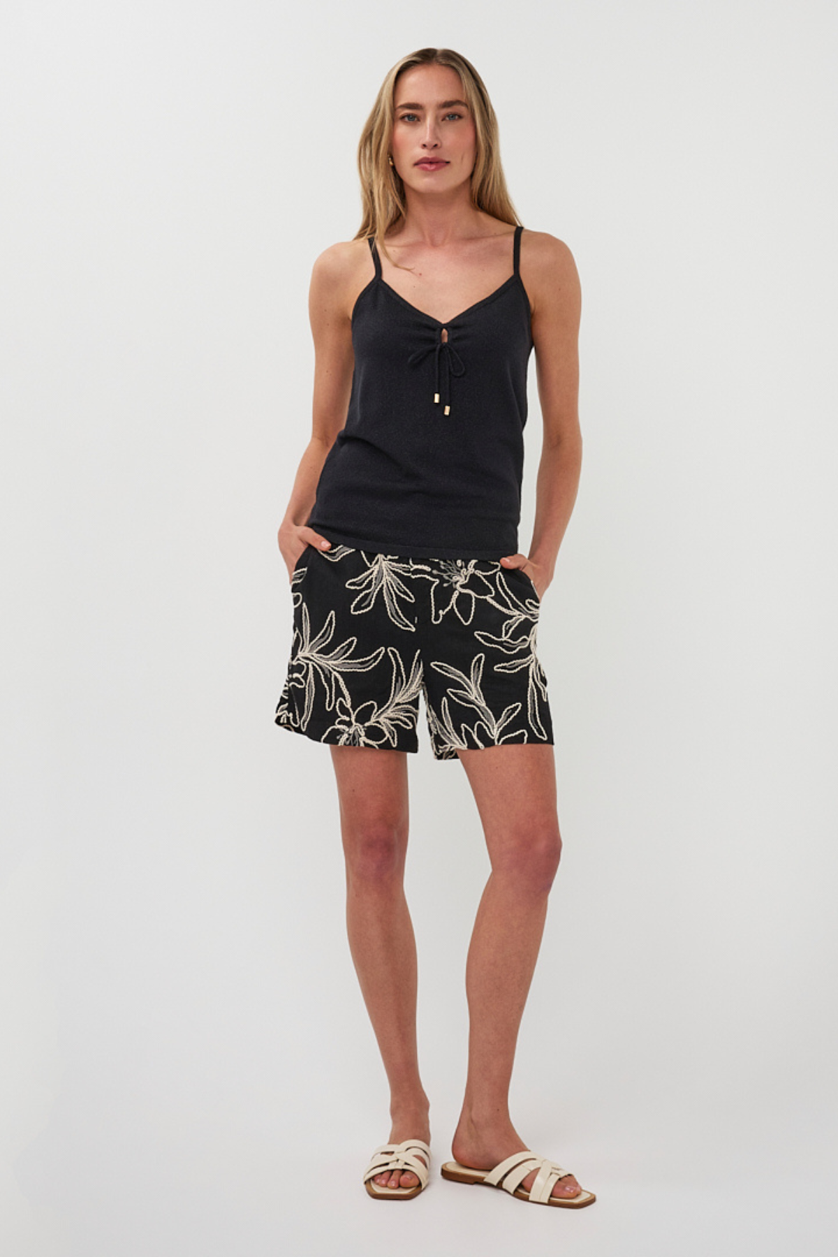 Woman wearing a black tank top and leaf-patterned shorts on a white background