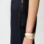 Person wearing a gold bracelet on a plain background