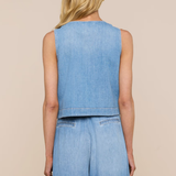 Person wearing a sleeveless denim top and wide-leg jeans on a beige background