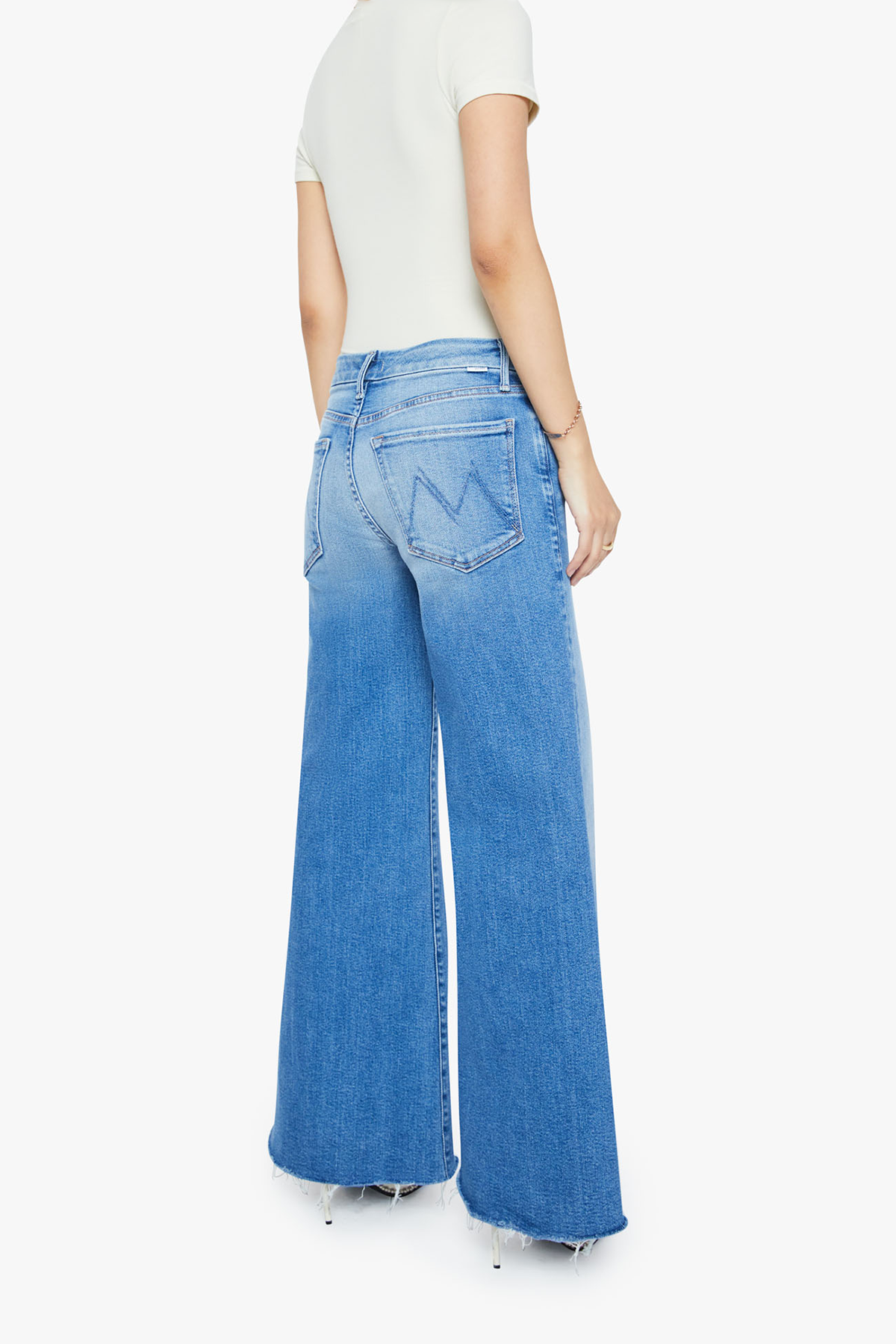 Person wearing blue jeans and a white top on a white background