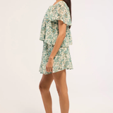Woman wearing a floral top and skirt on a white background - side angle 
