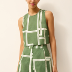 Woman wearing a green and white geometric patterned outfit on a plain background