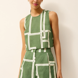 Woman wearing a green and white geometric patterned outfit on a plain background