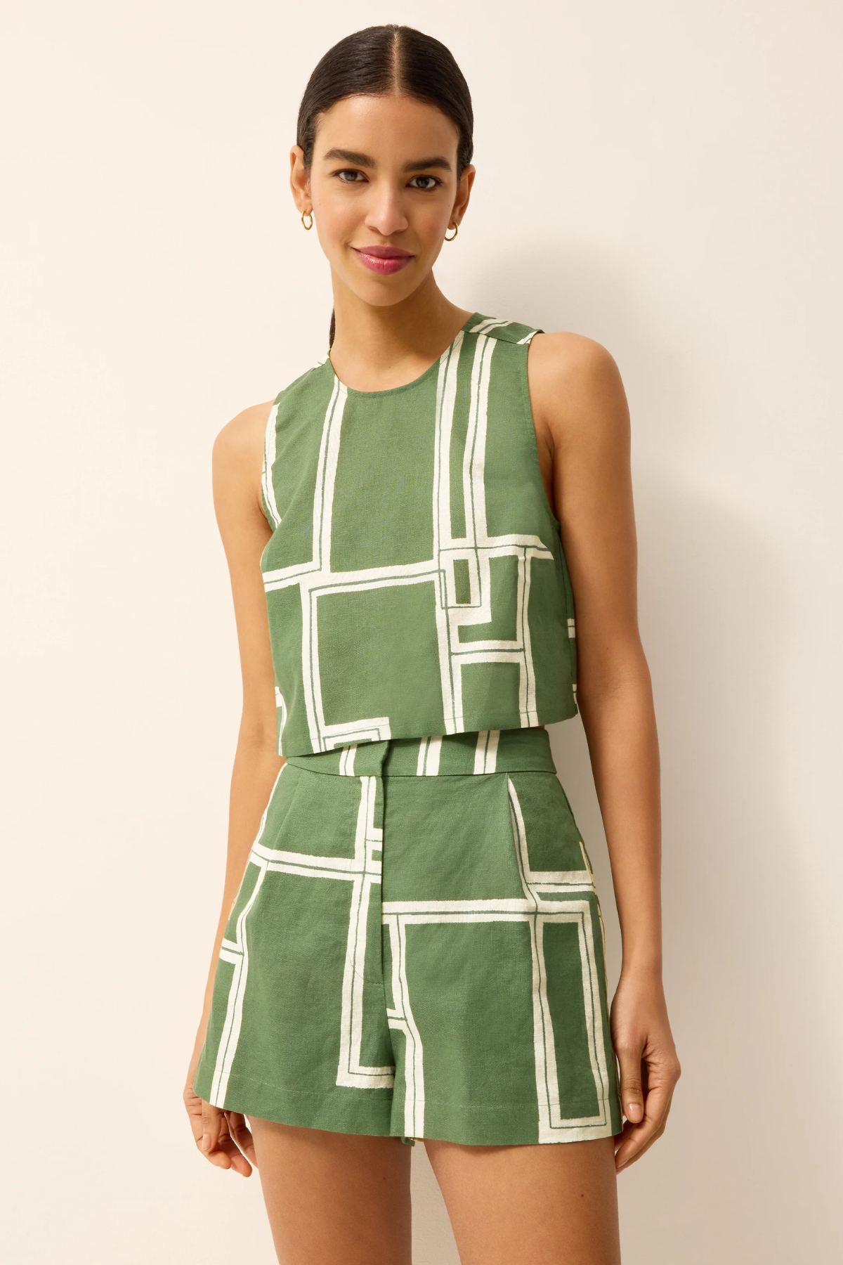 Woman wearing a green and white geometric patterned outfit on a plain background