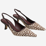 A pair of pointed-toe slingback pumps featuring a brown and beige animal print pattern with dark brown straps and heels, displayed against a light gray background.