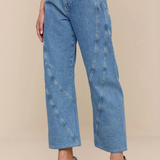 Person wearing blue jeans and matching denim shoes on a beige background