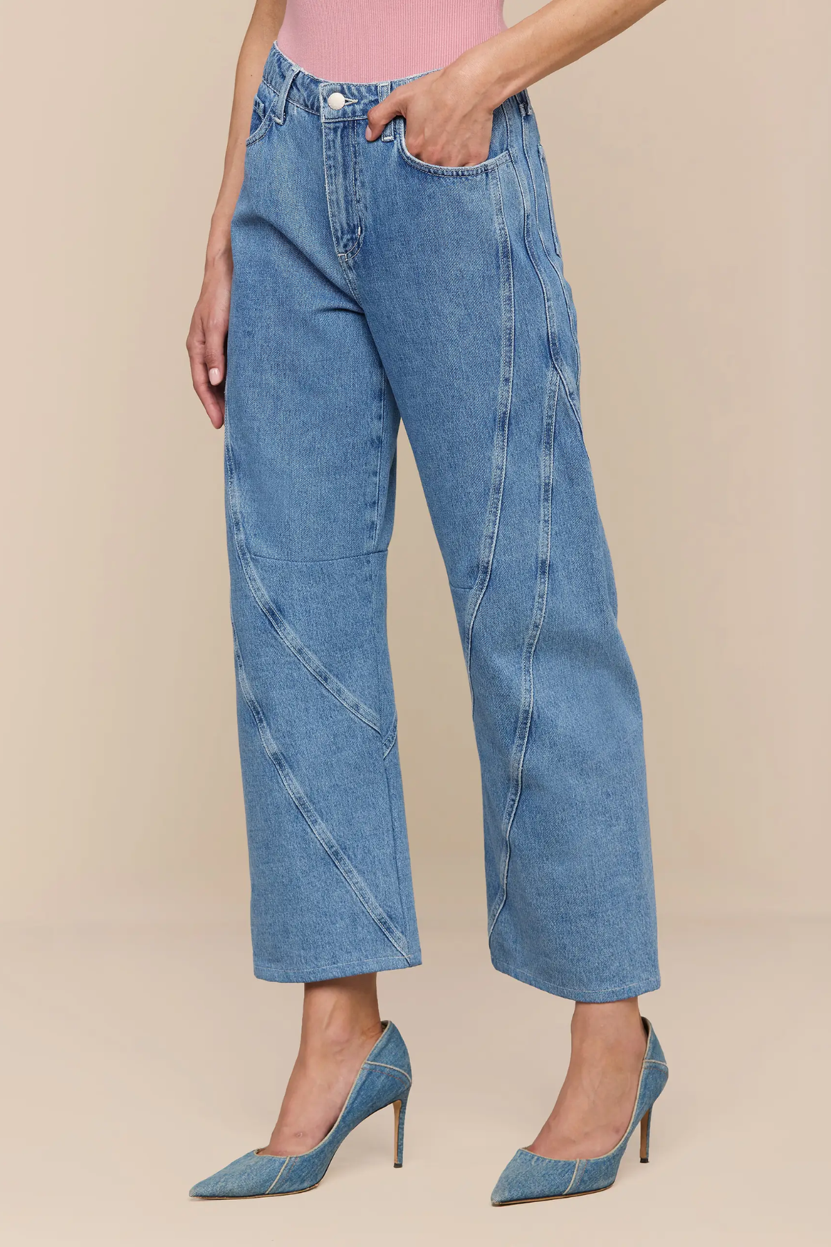 Person wearing blue jeans and matching denim shoes on a beige background