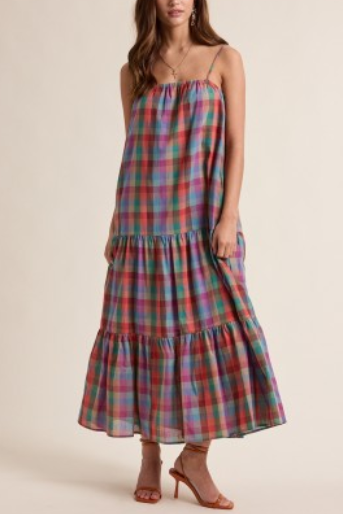 Multicolored plaid dress worn by a model on a beige background