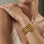 Woman wearing a gold bracelet on a neutral background
