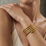 Woman wearing a gold bracelet on a neutral background