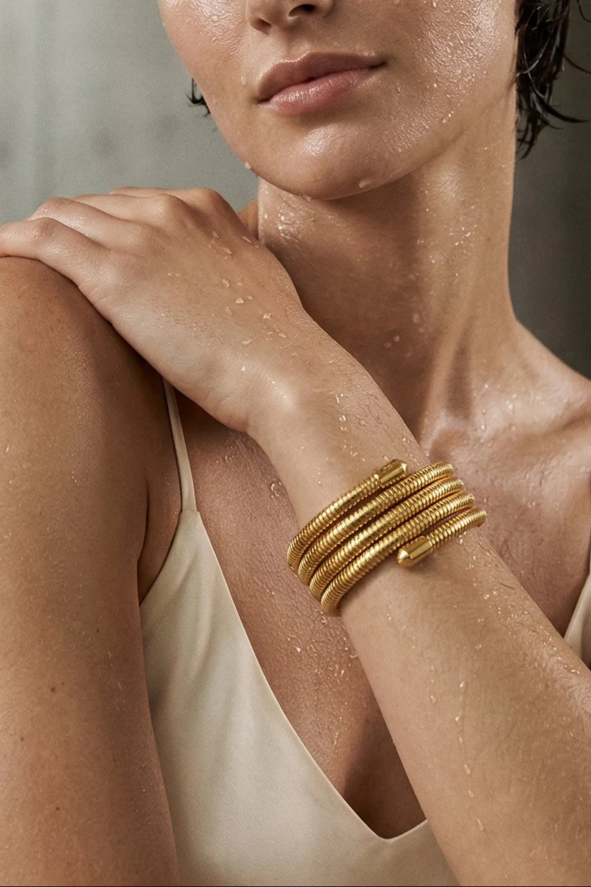 Woman wearing a gold bracelet on a neutral background