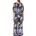 Woman wearing a navy floral jumpsuit on a white background