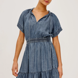 Woman wearing a denim dress against a plain background