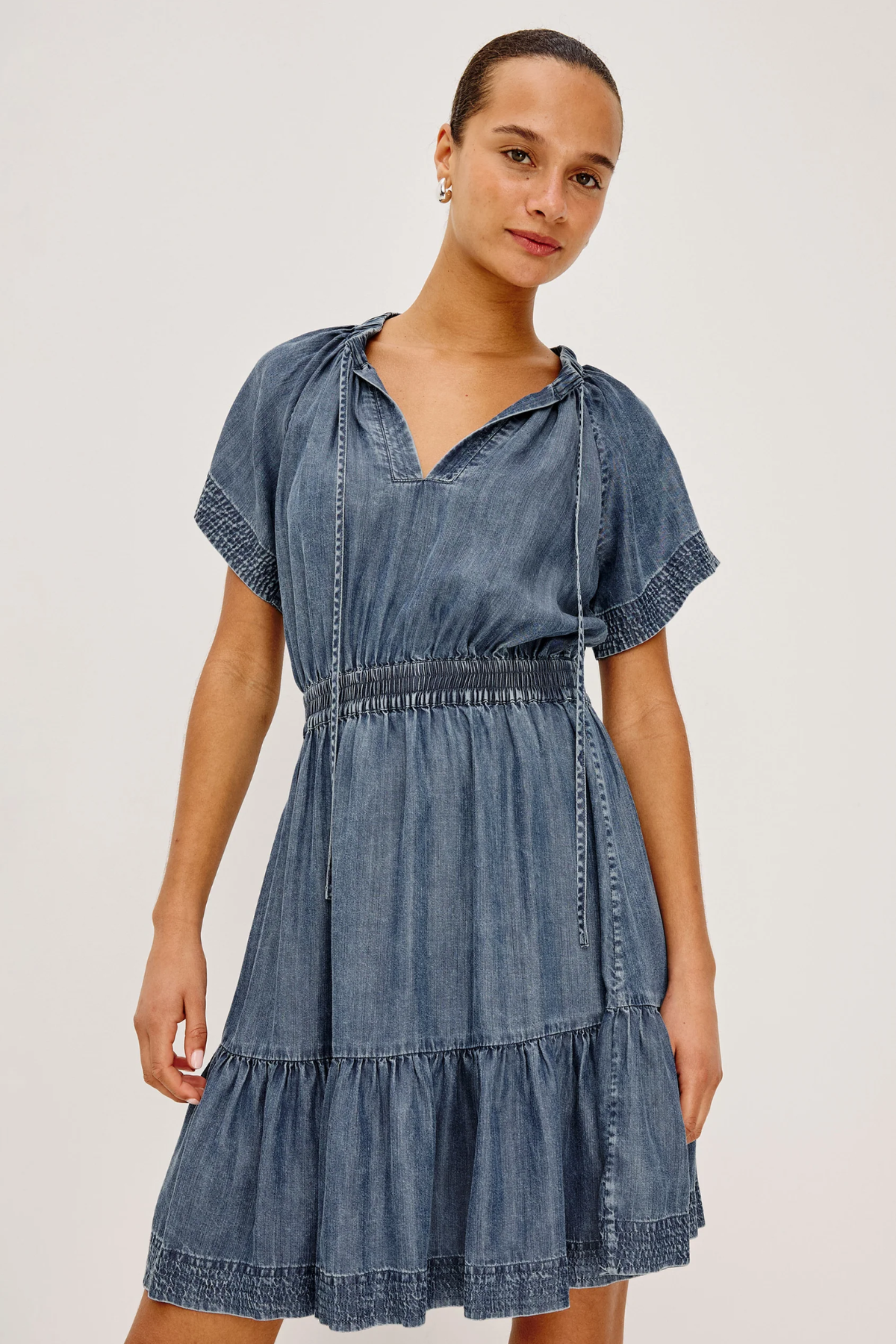 Woman wearing a denim dress against a plain background