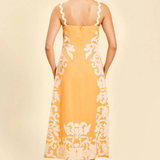 back of woman in orange embroidered midi dress