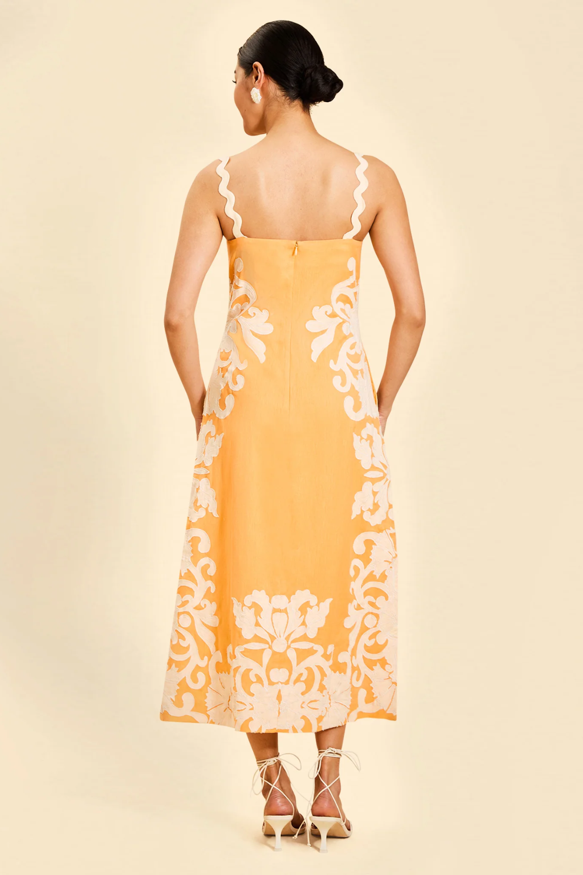 back of woman in orange embroidered midi dress