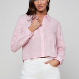 Woman wearing a pink ribbed blouse and white shorts on a gray background