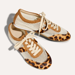 Pair of sneakers with leopard print soles on a light background