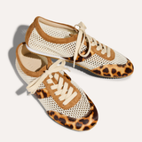 Pair of sneakers with leopard print soles on a light background