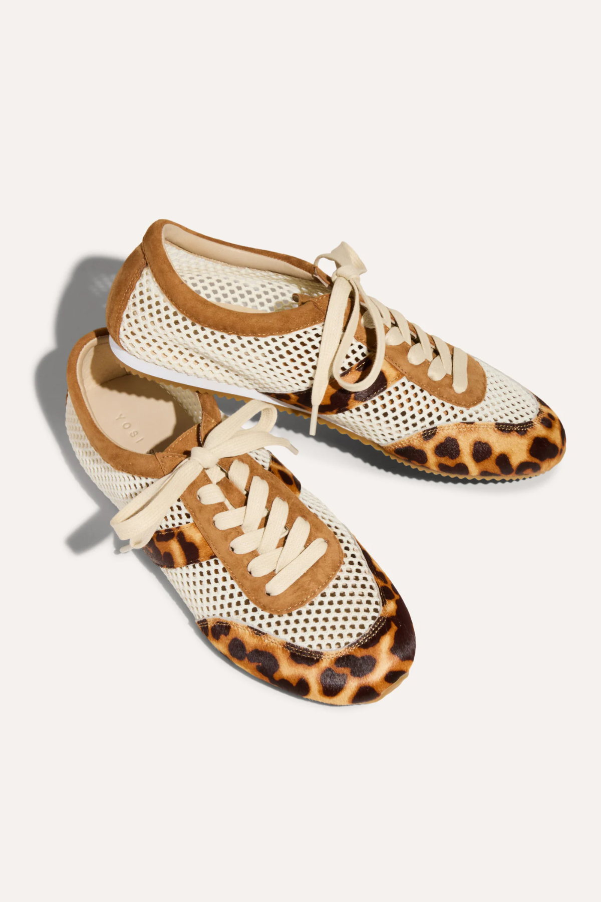 Pair of sneakers with leopard print soles on a light background