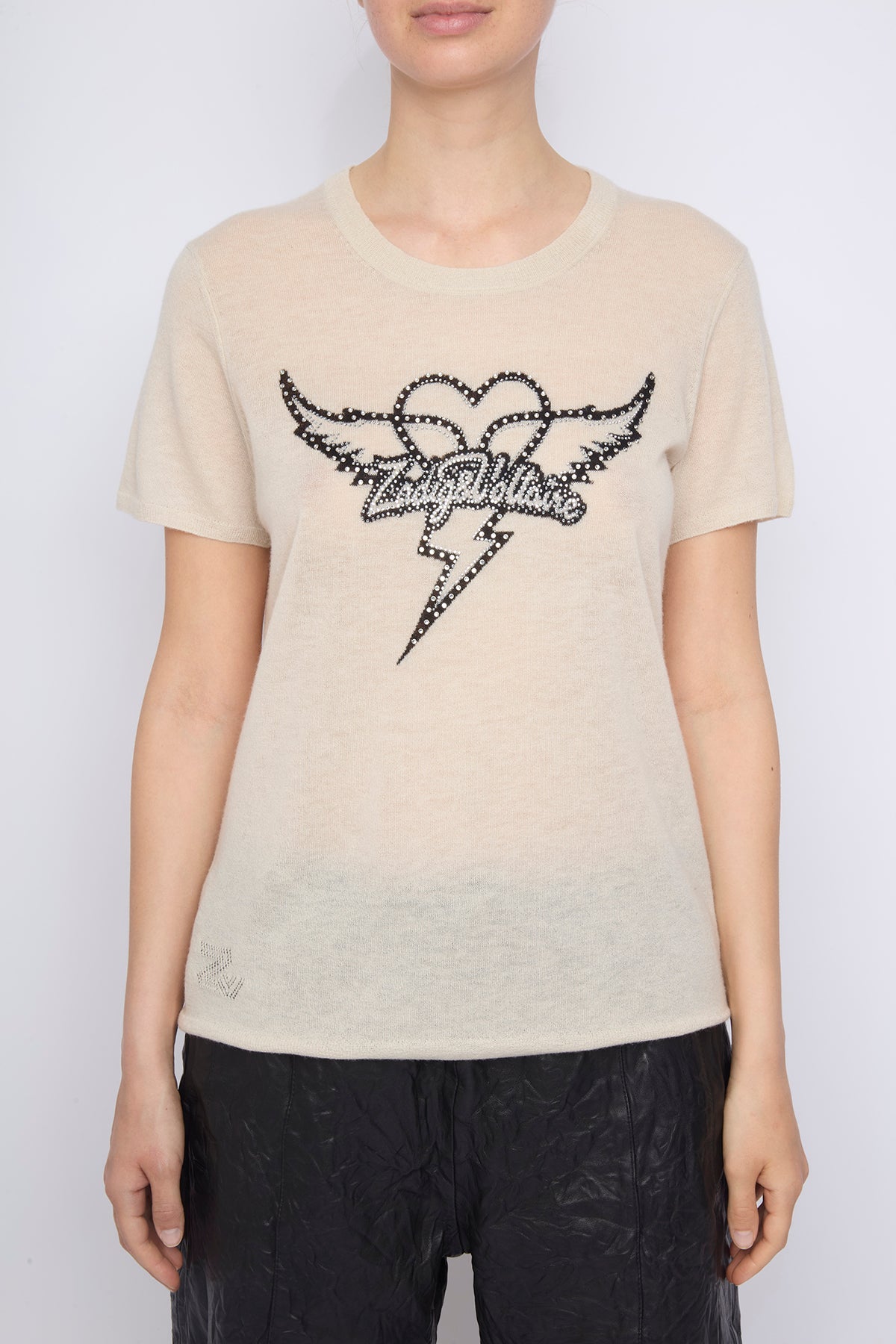 Person wearing a beige t-shirt with a black graphic design on a white background