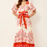 Woman wearing a floral dress with a red belt on a white background