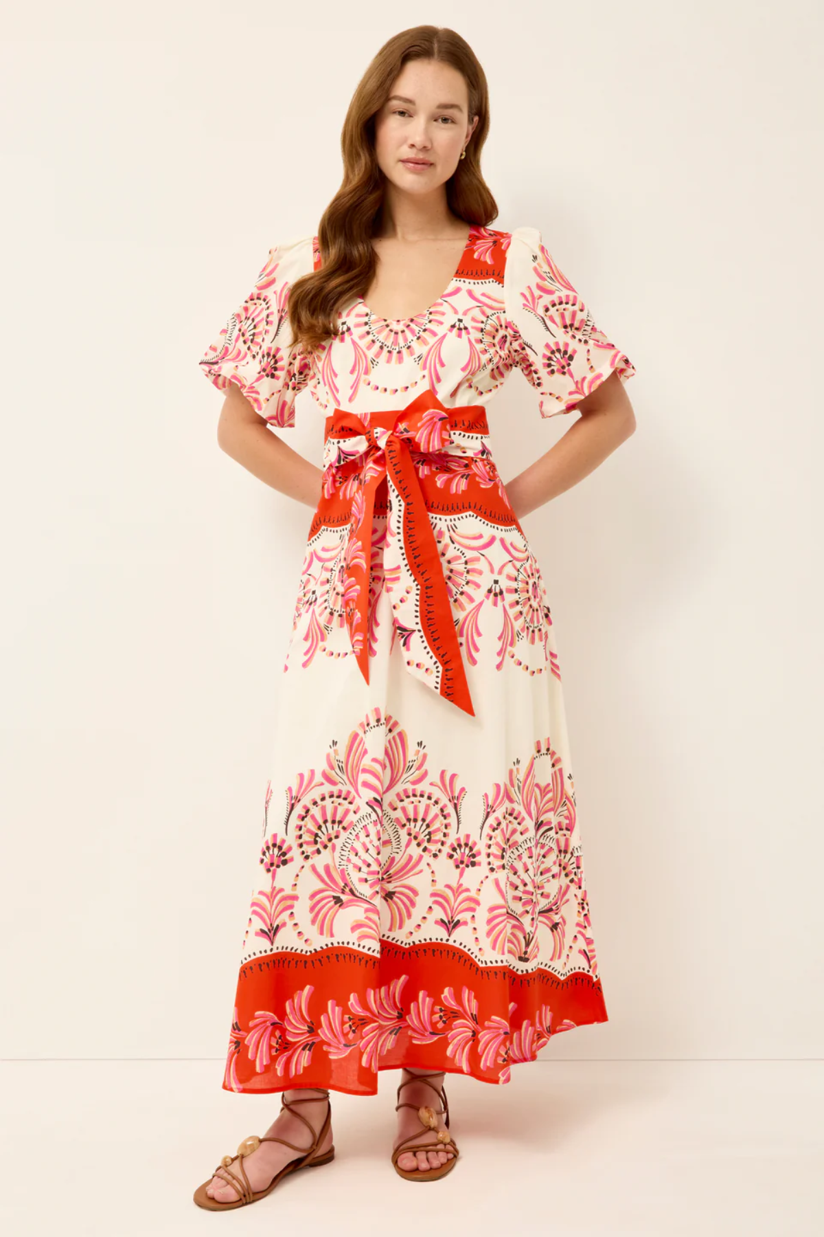 Woman wearing a floral dress with a red belt on a white background