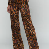 A model wearing a brown and black leopard print jumpsuit with wide legs, shown from the waist down against a light gray studio background.
