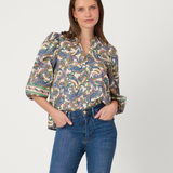 Woman wearing a patterned blouse and blue jeans on a white background