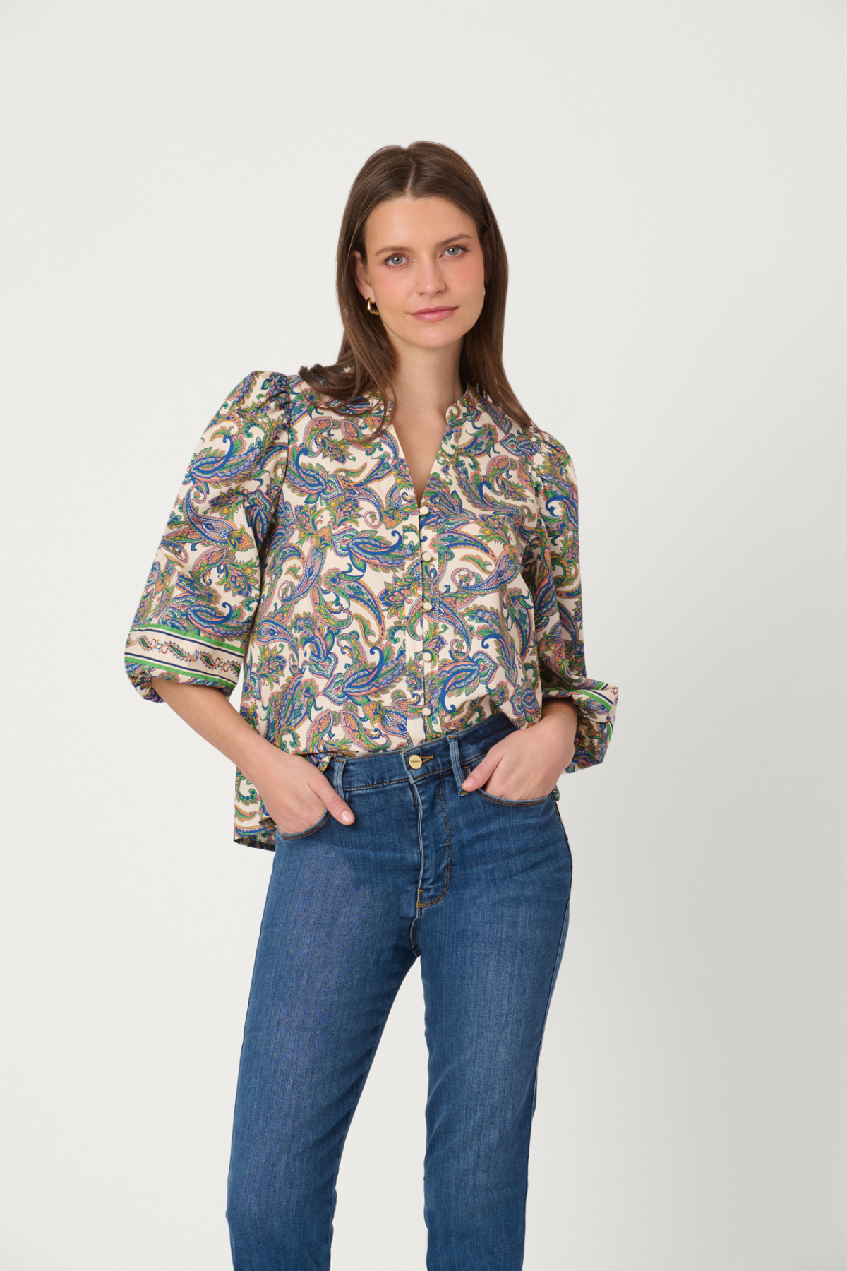 Woman wearing a patterned blouse and blue jeans on a white background