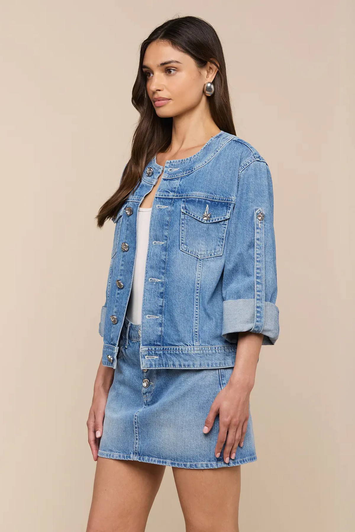Woman wearing a denim jacket and skirt on a beige background