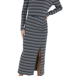 A woman modeling a long-sleeve midi dress with horizontal navy, beige, and white stripes, featuring a mock neck, puffed shoulders, and a front slit, paired with beige heeled sandals against a white background.