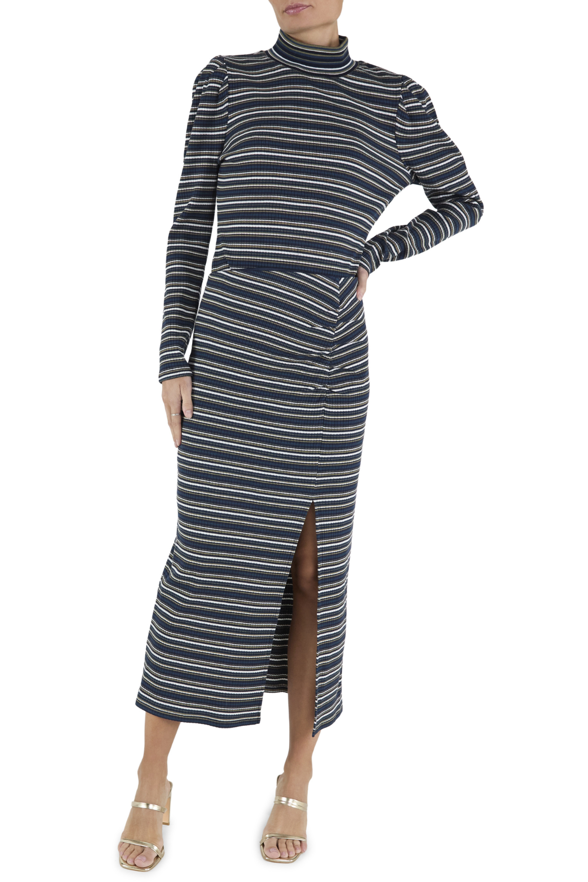 A woman modeling a long-sleeve midi dress with horizontal navy, beige, and white stripes, featuring a mock neck, puffed shoulders, and a front slit, paired with beige heeled sandals against a white background.