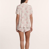 Woman wearing a floral pajama set on a plain background