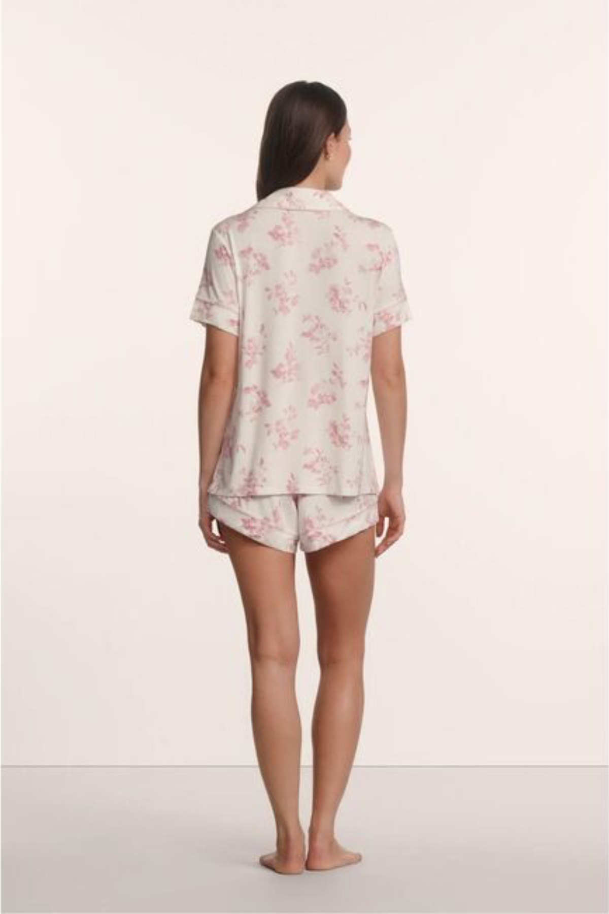Woman wearing a floral pajama set on a plain background
